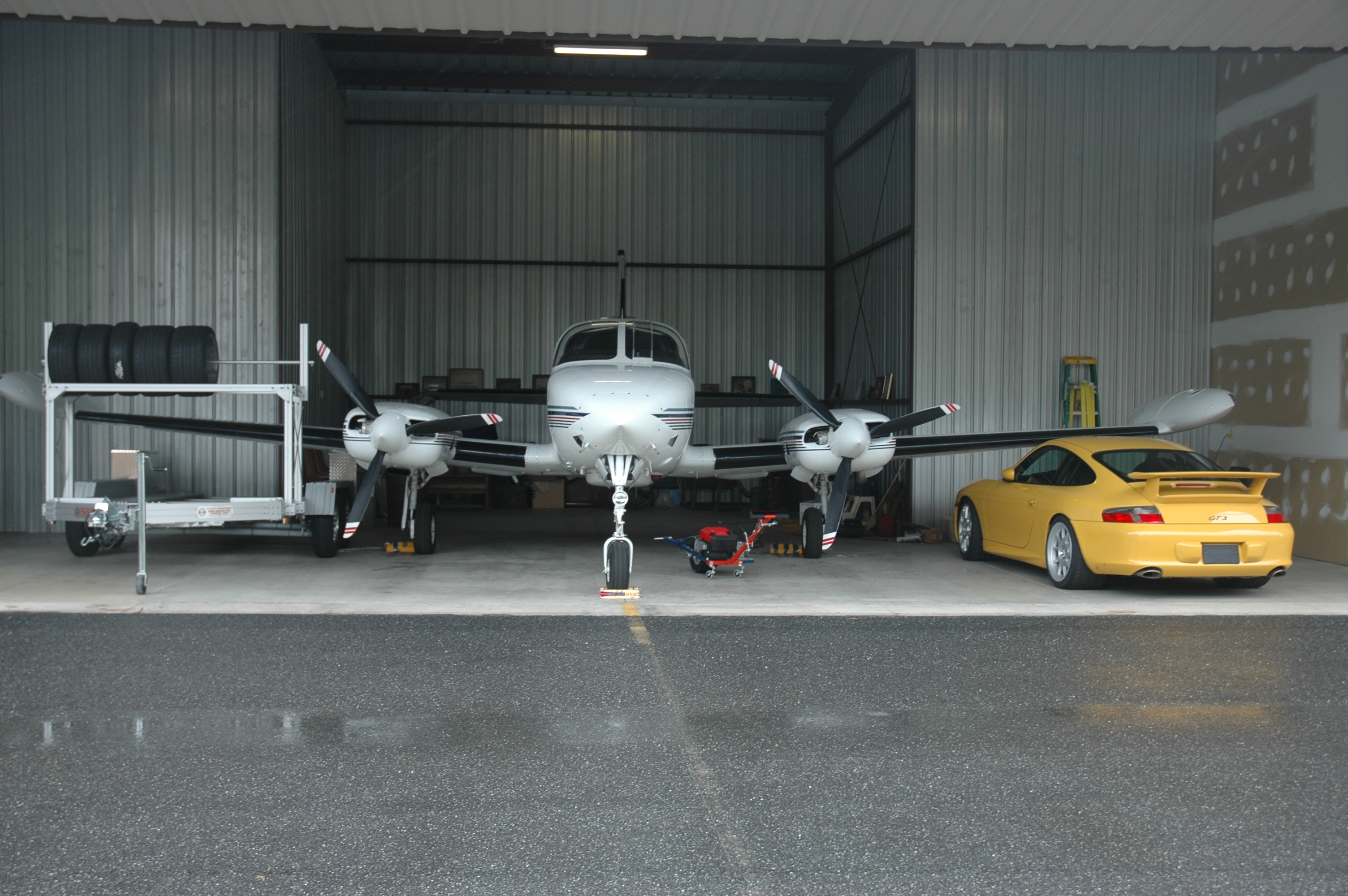Porsche GT3 and open trailer parked beside a private plane in hangar